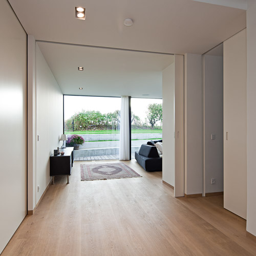 Sliding doors with integrated handles disappear into the wall and ceiling